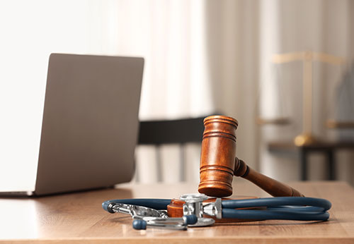 Gavel and stethoscope on a table with a laptop, representing Phillips & Nemajovsky Law in Lee County, GA