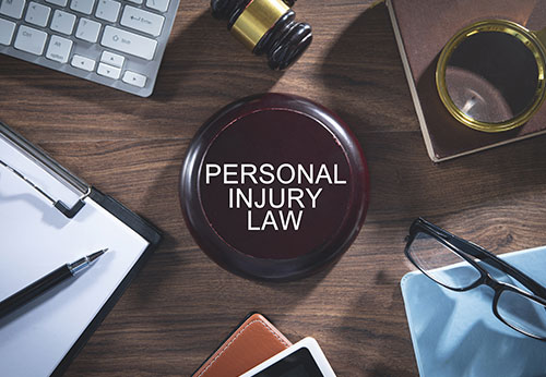 Top-down view of a personal injury law gavel, legal documents, and office desk accessories.